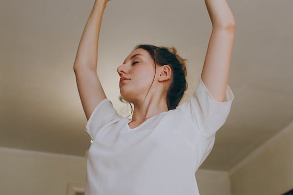 Person stretching in a bright, minimalist room.